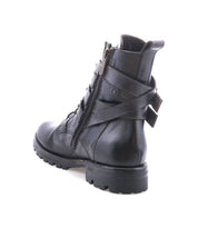 A black leather "Grab" combat boot by Bed|Stü features a side zipper, lace-up front, rugged Vibram sole, and two studded buckle straps at the ankle; shown angled from the back on a white background.