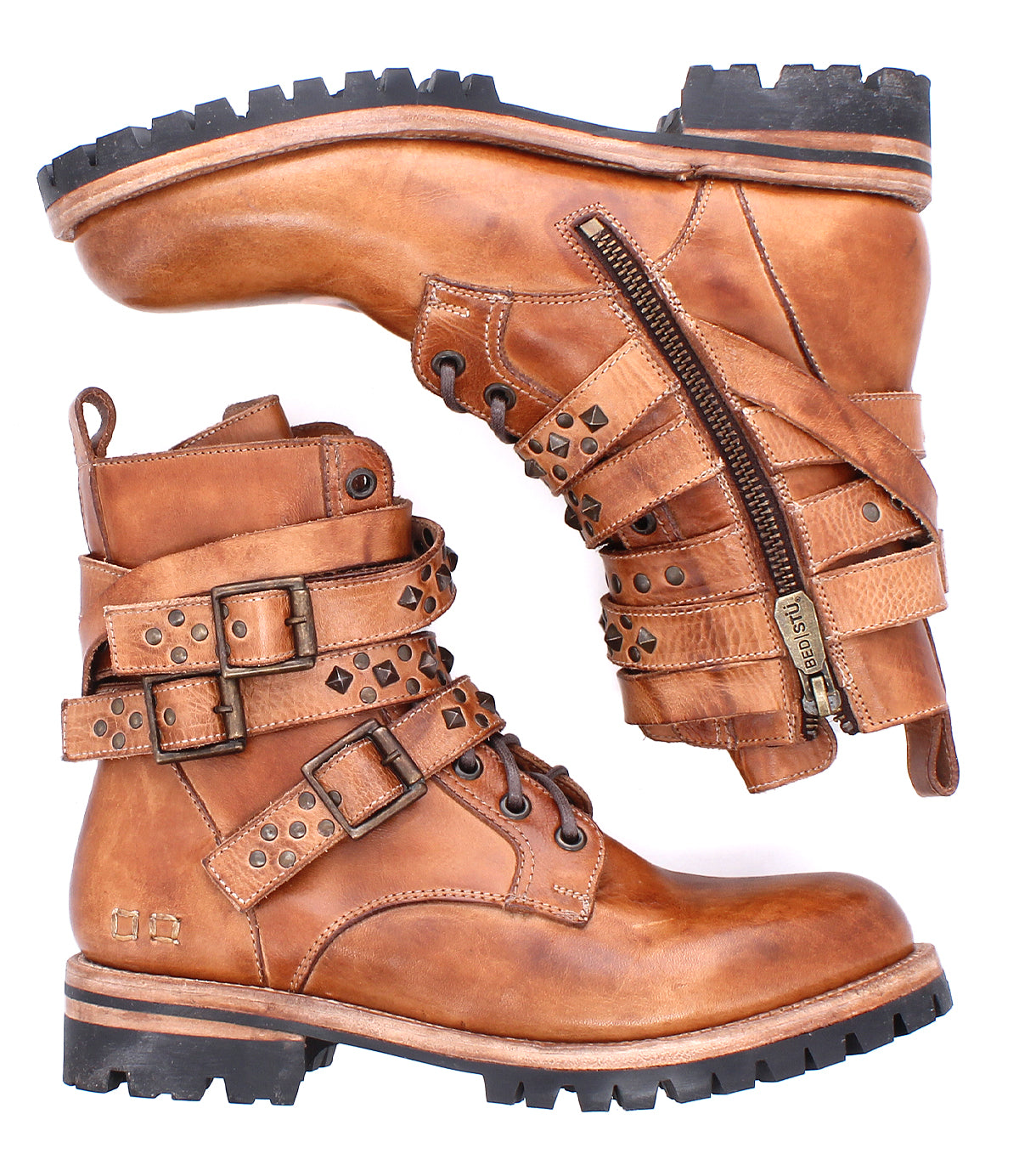 A pair of Bed|Stü Grab rugged brown leather combat boots with laces, studded buckle straps, and a side zipper, featuring sturdy studs and a durable Vibram sole, displayed against a white background.