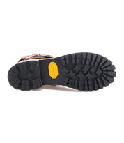 The image shows the bottom view of the Bed|Stü Grab shoe in brown, featuring a black, rugged Vibram sole with a yellow Vibram logo at the center.
