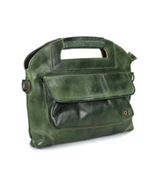 The Bed|Stü Greenway is a green full-grain leather briefcase featuring a built-in handle, prominent front flap pocket, and visible stitching, displayed on a white background. It is designed with a convenient zip-top closure for added security.