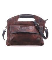 The Bed|Stü Greenway is a brown leather shoulder bag crafted from full-grain leather with black accents, featuring a spacious front pocket, adjustable crossbody strap, integrated top handle, and a secure zip-top closure to keep your essentials safe.