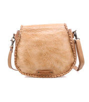 The Bed|Stü Half Moon EM is a light brown leather saddlebag crossbody purse featuring an embossed foliage pattern, whipstitch trim, and adjustable strap, displayed on a white background.