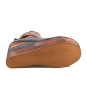 The image displays the sole view of the Bed|Stü Harmonious wedge, showcasing its textured rubber bottom, a visible buckle on the upper leather section, and a sculpted wood base that provides both style and support.