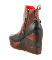 Introducing the Harmonious by Bed|Stü: a platform wedge ankle boot crafted with brown and black leather uppers, featuring a side zipper, sculpted wood base details, a platform sole, and a bold red inner lining.