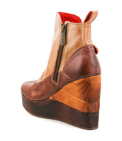 The Bed|Stü Harmonious is a brown leather platform wedge ankle boot with a zipper and a sculpted wooden base, featuring smooth leather uppers and a wooden platform heel, shown from the back against a white background.