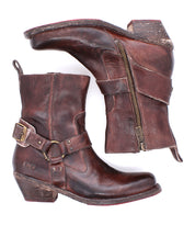 A pair of Bed|Stü Homage boots crafted from rich, worn leather with harness straps, buckles, and side zippers, featuring a square toe design and shown from both the side and bottom views.