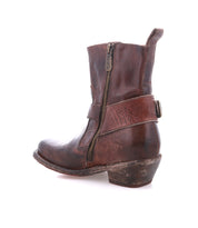 The Bed|Stü Homage is a single distressed brown rich leather ankle boot featuring a harness strap, side zipper, visible stitching, and a low heel, displayed against a white background.