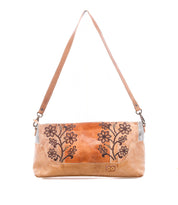 The Bed|Stü Hyperbolic is a tan handcrafted leather shoulder bag featuring floral embroidery, a rectangular silhouette, and a single wide strap, displayed against a white background for a distinctive touch of bohemian charm.