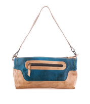 The Hyperbolic by Bed|Stü is a blue and tan leather shoulder bag, featuring a single strap and a front zippered pocket. Handcrafted in a subtle bohemian style, it is displayed against a white background.