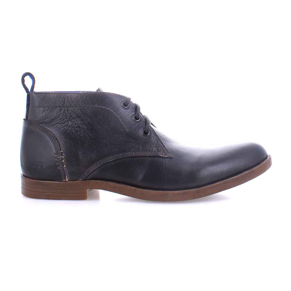 The Bed|Stü Illiad chukka boot, shown in profile on a white background, features black leather, a comfortable outsole with a brown sole, three eyelets for lacing, and a pull tab at the heel. This modern lace-up design blends classic style with everyday comfort.