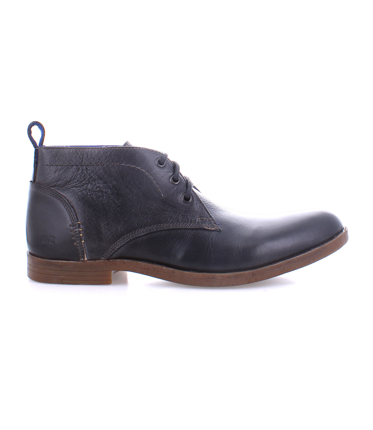 The Bed|Stü Illiad chukka boot, shown in profile on a white background, features black leather, a comfortable outsole with a brown sole, three eyelets for lacing, and a pull tab at the heel. This modern lace-up design blends classic style with everyday comfort.