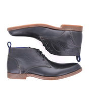 Two Illiad black leather chukka ankle boots by Bed|Stü, featuring brown soles, are shown from a side view, stacked one above the other against a white background. These modern lace-up boots offer comfortable outsoles and blend timeless style with everyday comfort.