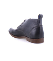 The Bed|Stü Illiad is a single black leather chukka ankle boot, featuring a modern lace-up design and a comfortable outsole, displayed from the back and side against a white background.