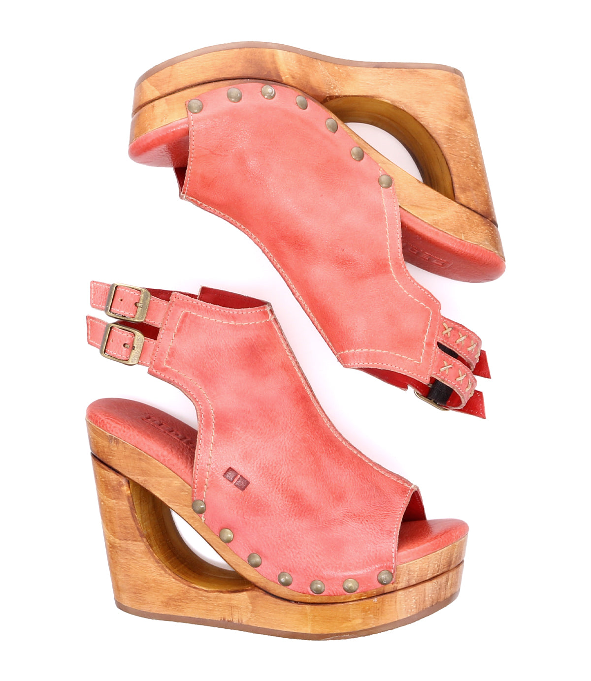 The Imelda sandals by Bed|Stü feature a coral pink leather upper with wooden wedge platforms, an open-toe design, cut-out sides, adjustable ankle buckles, and metal stud accents, presented in a side view against a white background.