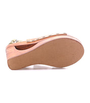 The Imelda wedge sandal by Bed|Stü is shown from the bottom, highlighting its light brown, textured sole and visible wooden platform heel adorned with metallic studs along the side. This stylish design features an open-toe silhouette and adjustable ankle buckles for a secure fit.