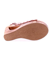 The Bed|Stü Imelda sandal is shown from the bottom, highlighting its textured sole and curved design in a reddish-brown wooden wedge. The open-toe silhouette adds a stylish touch to its overall look.