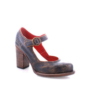 The Bed|Stü Ishtar is a single brown leather Mary Jane pump featuring a chunky block heel, red interior lining, and an adjustable buckle strap over the instep, displayed on a white background.