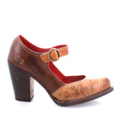 The Ishtar by Bed|Stü is a brown leather Mary Jane pump with an adjustable ankle strap and buckle, rounded toe, and sturdy wooden block heel. This shoe features visible wear on the front and boasts a striking red interior lining.