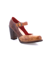 The Bed|Stü Ishtar is a brown leather Mary Jane pump featuring an adjustable strap and a chunky block heel, displayed against a white background.