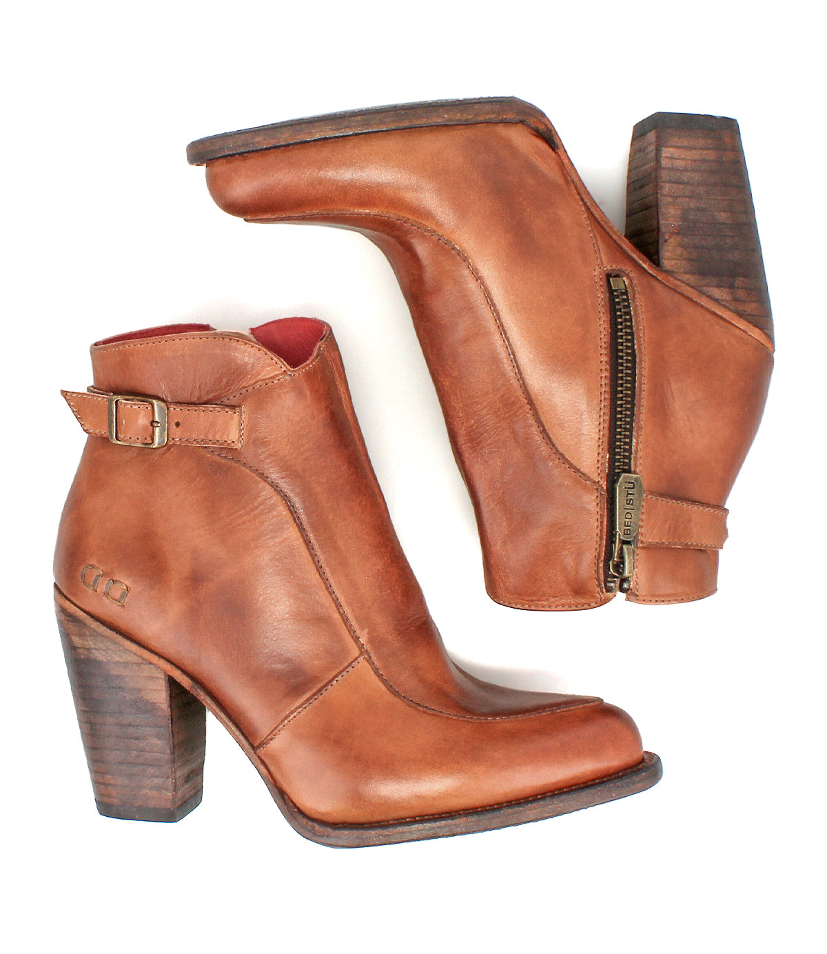 The Bed|Stü Isla is a pair of brown smooth leather ankle boots with block heels, side zippers, and buckle straps, displayed on a white background.
