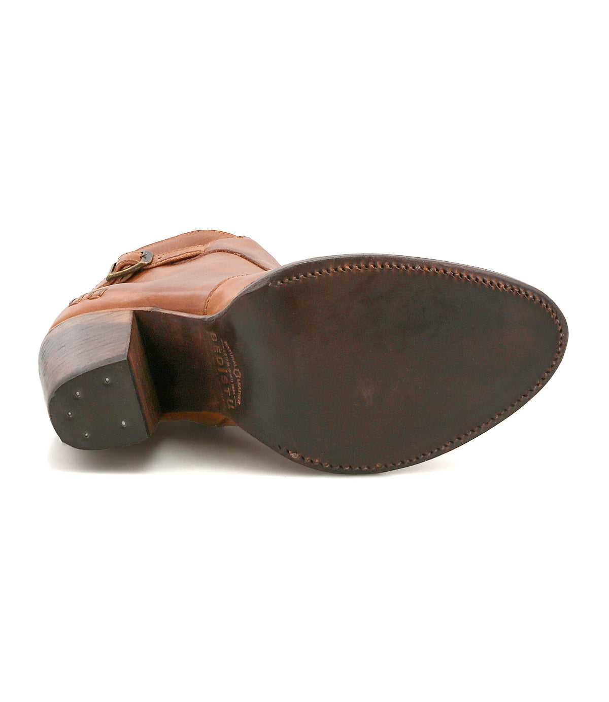 The image shows the underside of the Isla dress shoe by Bed|Stü, featuring brown smooth leather, a pointed toe, a stitched sole, and small metal tacks in the heel.