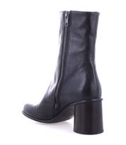 The Isodora by Bed|Stü is a black leather ankle boot with a side zipper and a chunky, mid-height heel, pictured from a rear side angle against a white background. These handcrafted boots feature Blake-stitched construction for lasting durability and a refined finish.