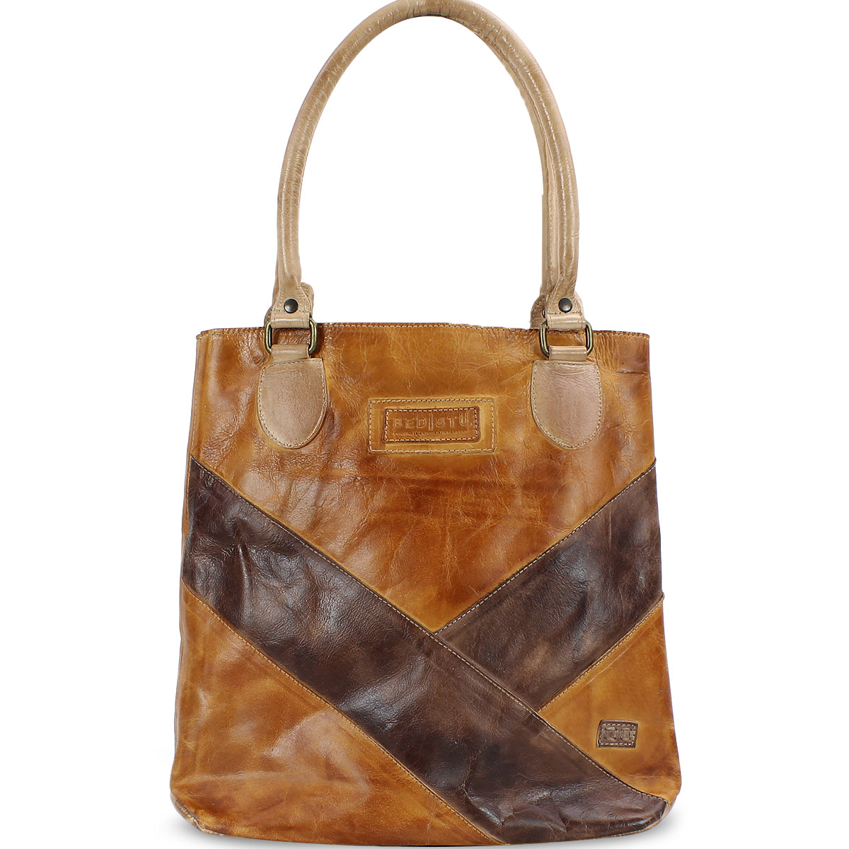 The Bed|Stü Italic is a brown leather tote bag with two handles, accented by diagonal dark brown and tan details, featuring an organic cotton lining and displayed against a white background.