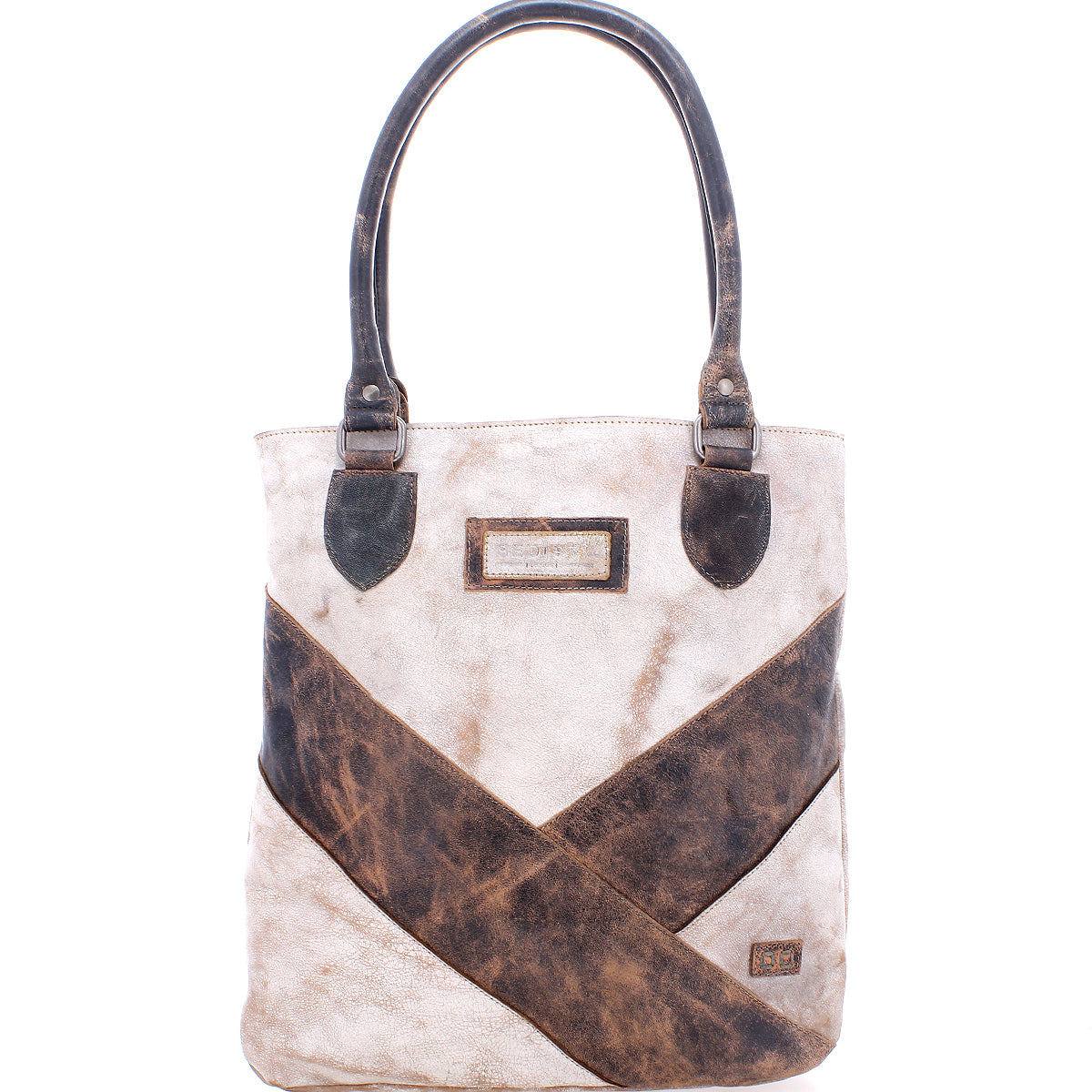Introducing the Italic tote bag by Bed|Stü: a beige and brown leather handbag with two handles, highlighted by a diagonal brown stripe and a rectangular label on the front. This stylish accessory features padded shoulder straps for enhanced comfort and an organic cotton lining, ensuring a touch of sustainable luxury.