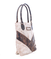 Introducing the Italic by Bed|Stü—a two-handle leather tote bag crafted in a patchwork of distressed beige and brown leather. It features padded shoulder straps, a rectangular branded label on the front, and an interior lined with organic cotton for enhanced comfort and eco-friendly appeal.