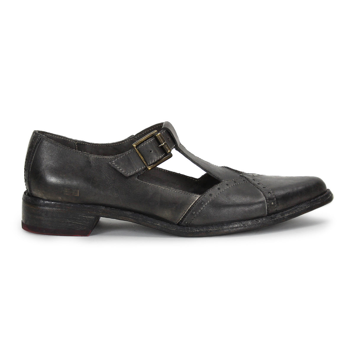 The Bed|Stü Jenny is a single black leather T-bar shoe with a buckle strap and low heel, featuring a cushioned insole for added comfort, shown in profile on a white background.