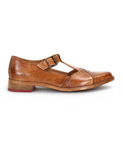 The Bed|Stü Jenny is a single brown leather Mary Jane-style T-strap shoe featuring a double buckle, low heel, cushioned insole, and red detailing on the outsole, displayed in profile against a white background.
