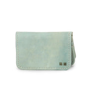 The Jeor card wallet by Bed|Stü features light blue rustic leather with visible stitching and two small metallic square accents on the bottom right corner. Designed with compact credit card slots, it is displayed against a white background.