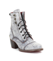 The Bed|Stü Judgement is a gray leather lace-up ankle boot featuring a textured finish, stacked block heel, cap toe, side eyelets, and striking red accents on the interior and sole.