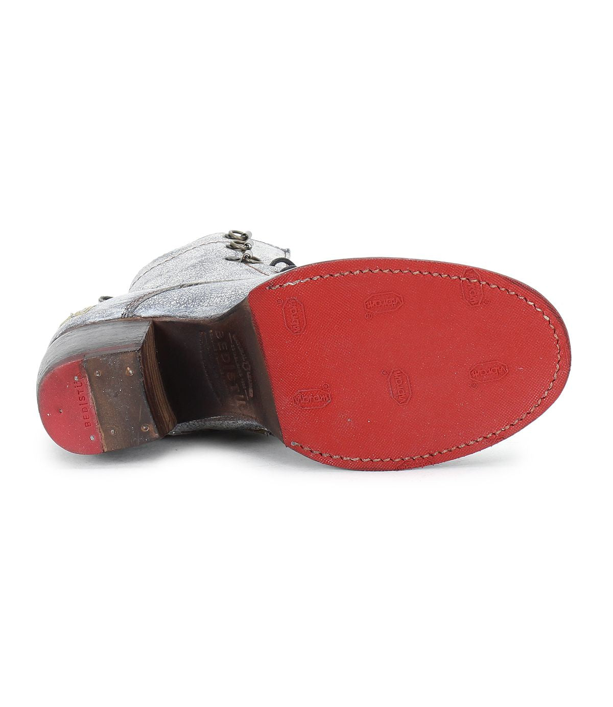 The Bed|Stü Judgement is a single leather lace-up boot displayed from the sole, highlighting its red bottom with visible stitching and tread patterns, cap toe, and stacked wooden block heel.