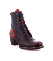 The Judgement boot by Bed|Stü is a brown leather lace-up style featuring a block heel, visible stitching, metal eyelets, cap toe detailing, and bold red accent panels, displayed against a white background.