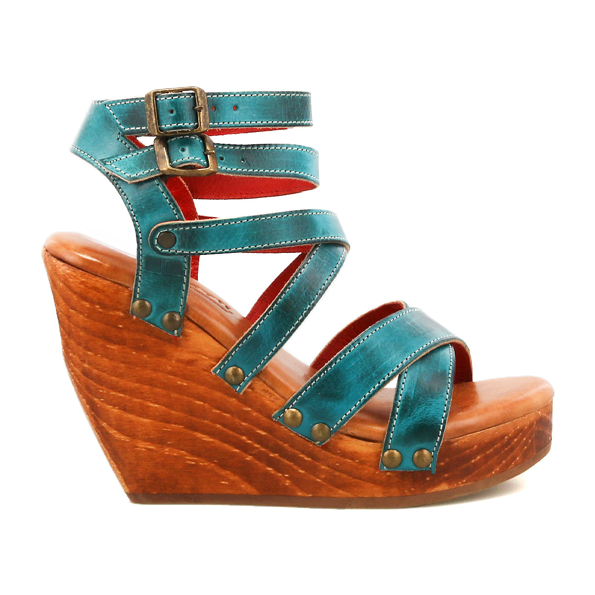 The Juliana II by Bed|Stü is a turquoise strappy wedge sandal with a wooden platform, featuring a strappy upper, two buckles at the ankle, and metallic rivet details on the straps.