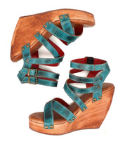 A pair of Bed|Stü Juliana II teal wedge sandals featuring a stylish strappy upper, wooden heels, and double buckle closures, displayed on a white background.