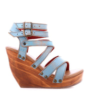 The Juliana II by Bed|Stü is a blue wedge platform sandal, featuring a stylish strappy upper, double ankle buckle closure, and a chic wooden wedge sole, shown in profile against a white background.