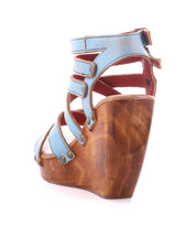 The Bed|Stü Juliana II is a blue platform sandal showcasing a strappy upper with rivet accents, a wooden wedge heel, and a chic cutout design, displayed from the side against a white background.