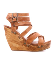 The Juliana II by Bed|Stü is a tan wedge sandal with a strappy leather upper accented by multiple straps, metal rivets, and double ankle buckles, all set on a stylish wood-textured wooden wedge platform sole.
