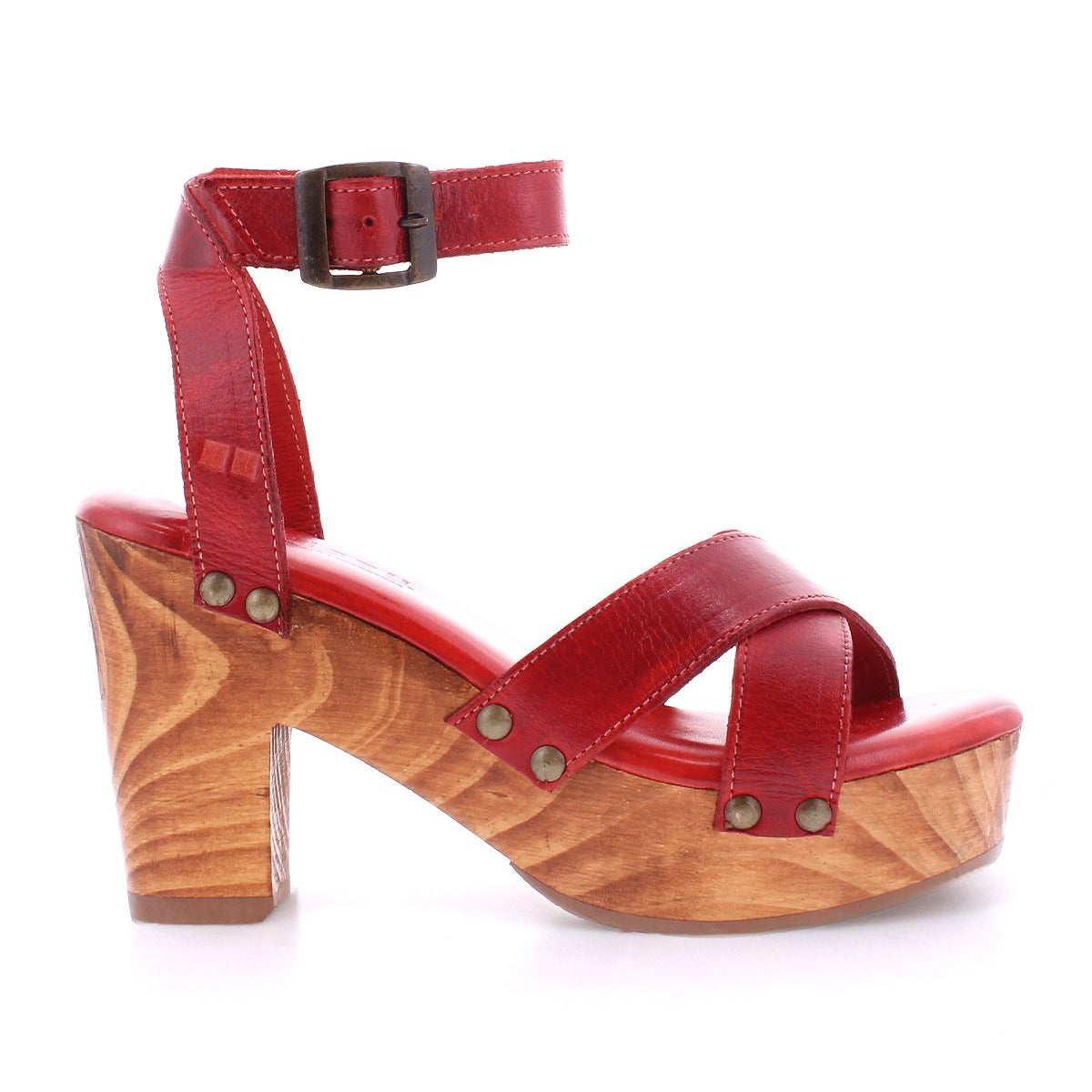 The Bed|Stü Kalah sandal is shown in a side view, featuring red leather with a sustainably sourced wooden platform heel, adjustable ankle strap, and metal rivet details.