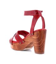 The Kalah by Bed|Stü is a red high-heeled sandal featuring a sustainably sourced wooden platform and heel, an adjustable ankle strap, and metal rivet details.