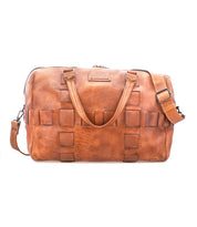 Bed|Stü Keg is a brown leather duffel bag crafted from premium vegetable tanned leather, showcasing a woven square pattern, two handles, detachable shoulder strap, and zippered top closure. Photographed against a white background, this travel bag combines timeless style with lasting durability.