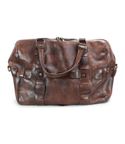 Bed|Stü Keg is a brown leather duffle bag crafted from vegetable-tanned leather, featuring dual handles, side rings for an optional shoulder strap, and a zippered top closure. This travel bag showcases a textured finish with visible stitching.