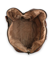An overhead view of the Bed|Stü Keg, an open brown duffle crafted from vegetable tanned leather with a tan fabric lining.