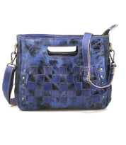 The Keiki crossbody bag by Bed|Stü features blue leather in a checkerboard pattern, adorned with metal rivets, a zip-top closure, an adjustable detachable shoulder strap, and a stylish cutout top handle.