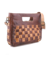 The Keiki crossbody bag by Bed|Stü features a brown leather construction with a woven checkerboard pattern, metal rivet accents, an adjustable strap, zip-top closure, and a convenient built-in top handle.