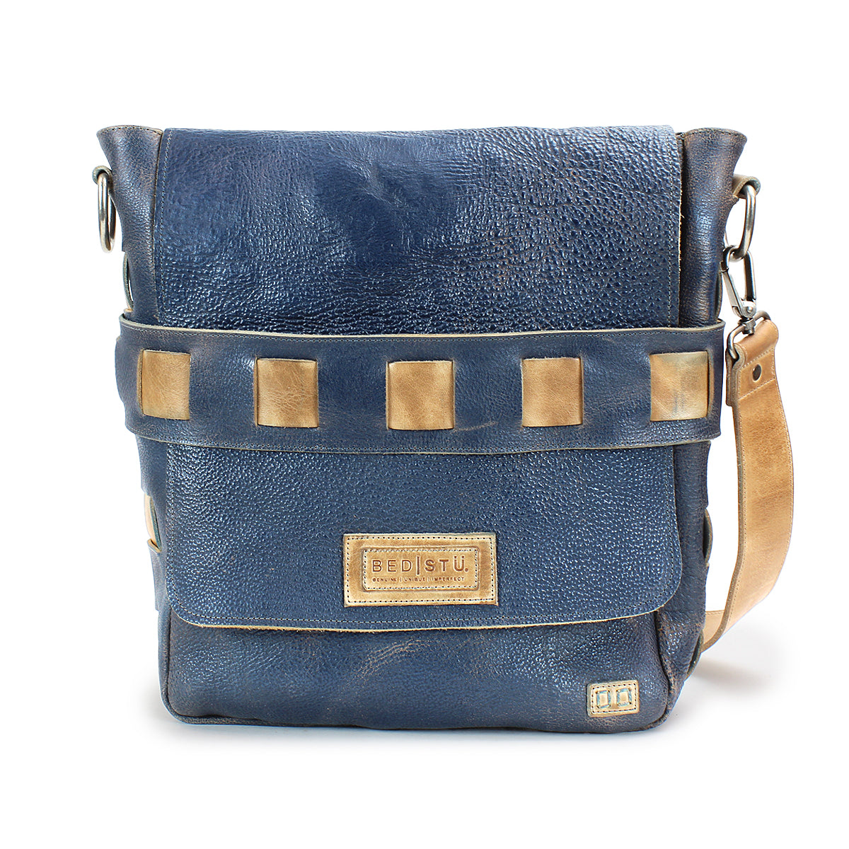 The Kure by Bed|Stü is a blue leather crossbody bag featuring a tan adjustable handwoven strap, square metal accents, and the Bed|Stü label on the front. Crafted from vegetable tanned leather, this distinctive accessory combines style and durability for everyday use.