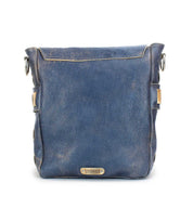 Introducing the Kure by Bed|Stü: a square blue leather crossbody bag with a flap top and metal logo plate on the front, featuring a stylish handwoven strap, photographed against a white background.