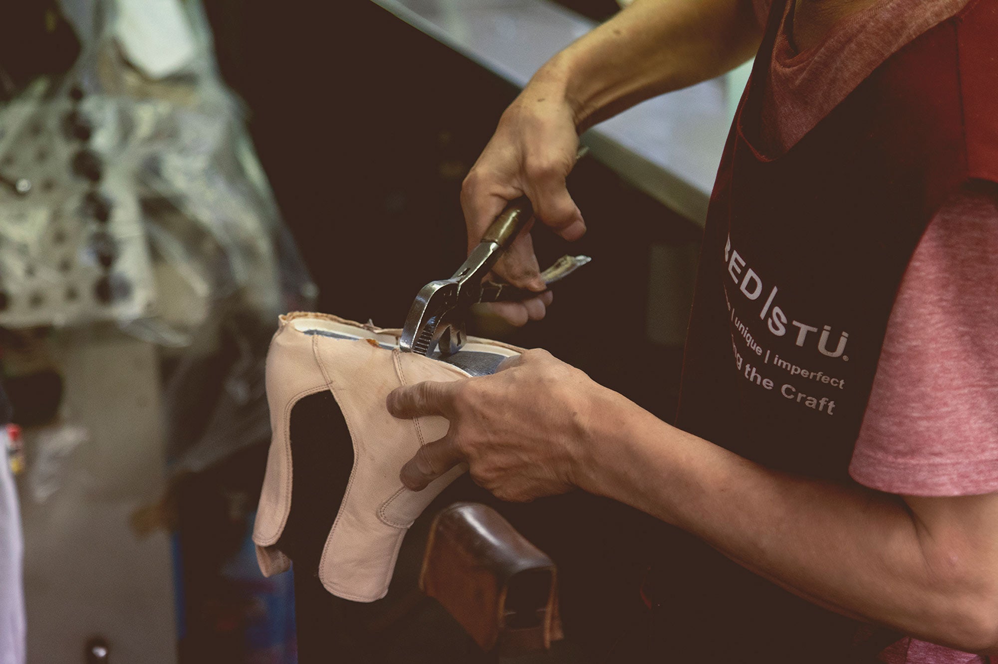 Craftsperson using pliers to shape a light leather shoe upper in a BED|STU workshop.